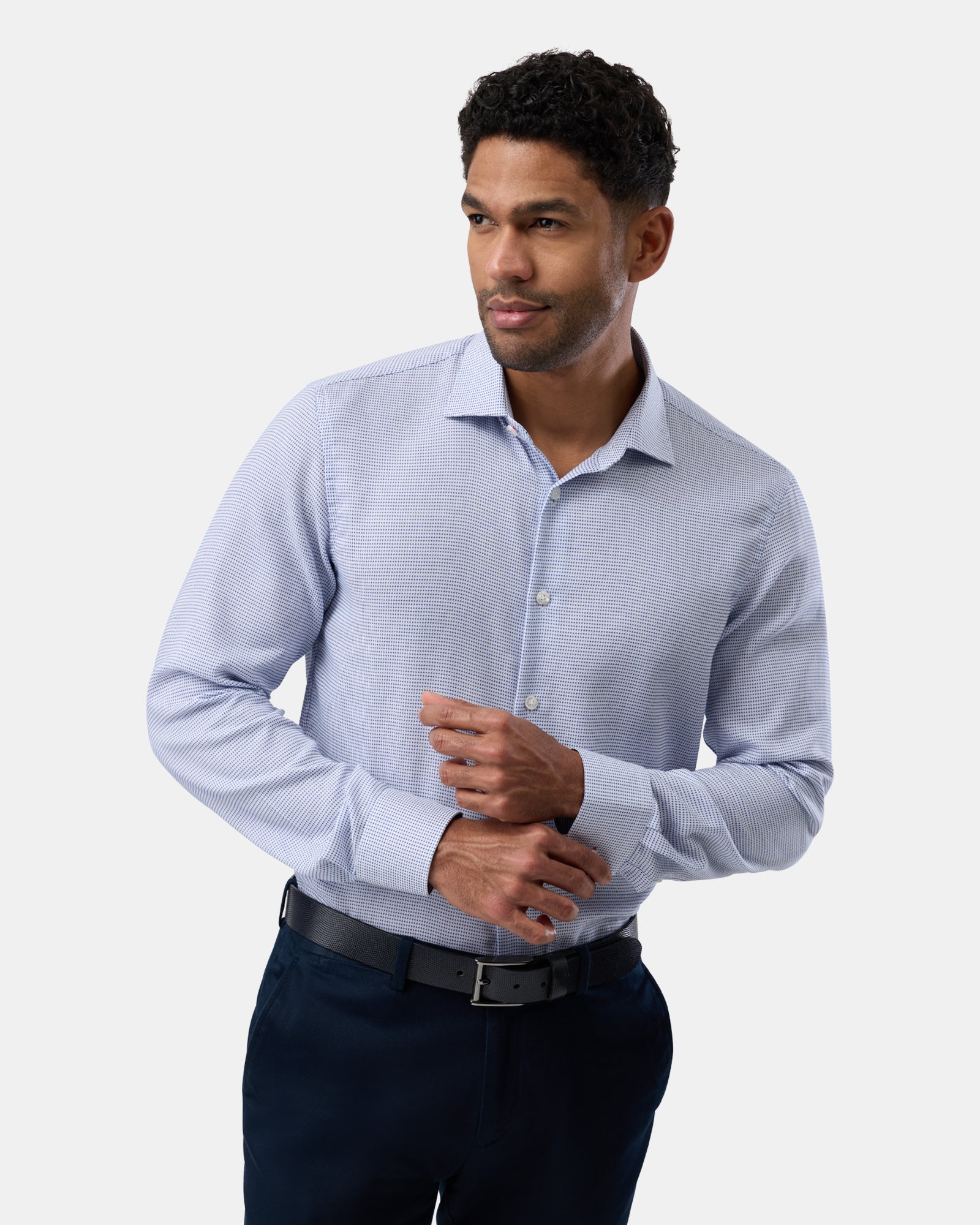 Wearing a light blue patterned shirt, man faces forward, neat and polished