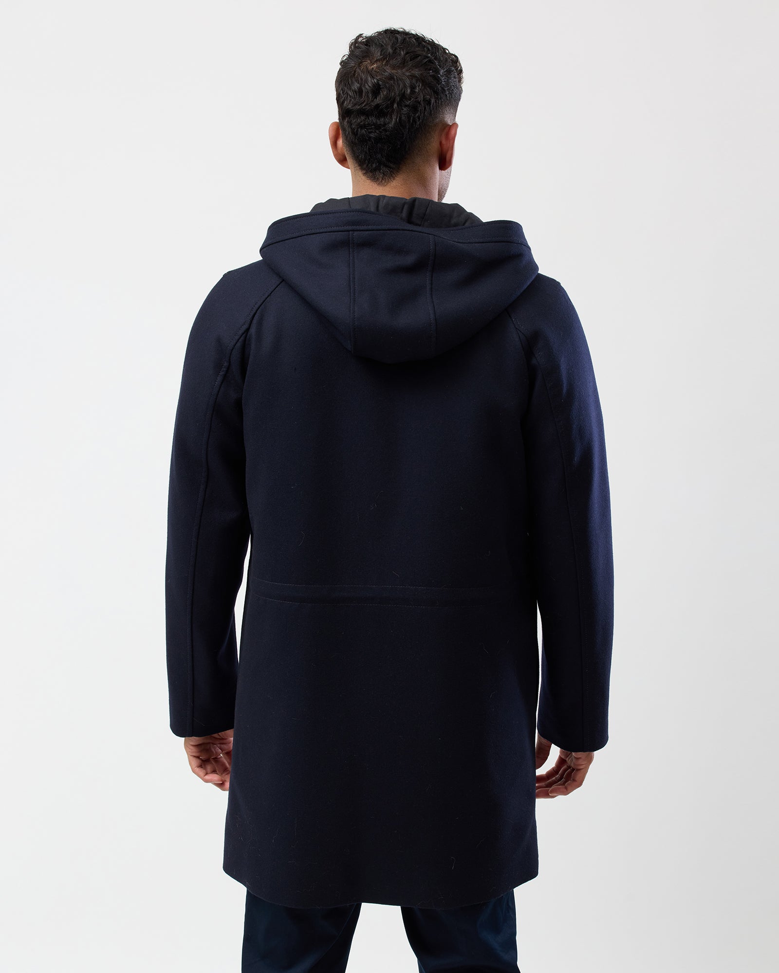Back view of man wearing navy wool blend hooded overcoat