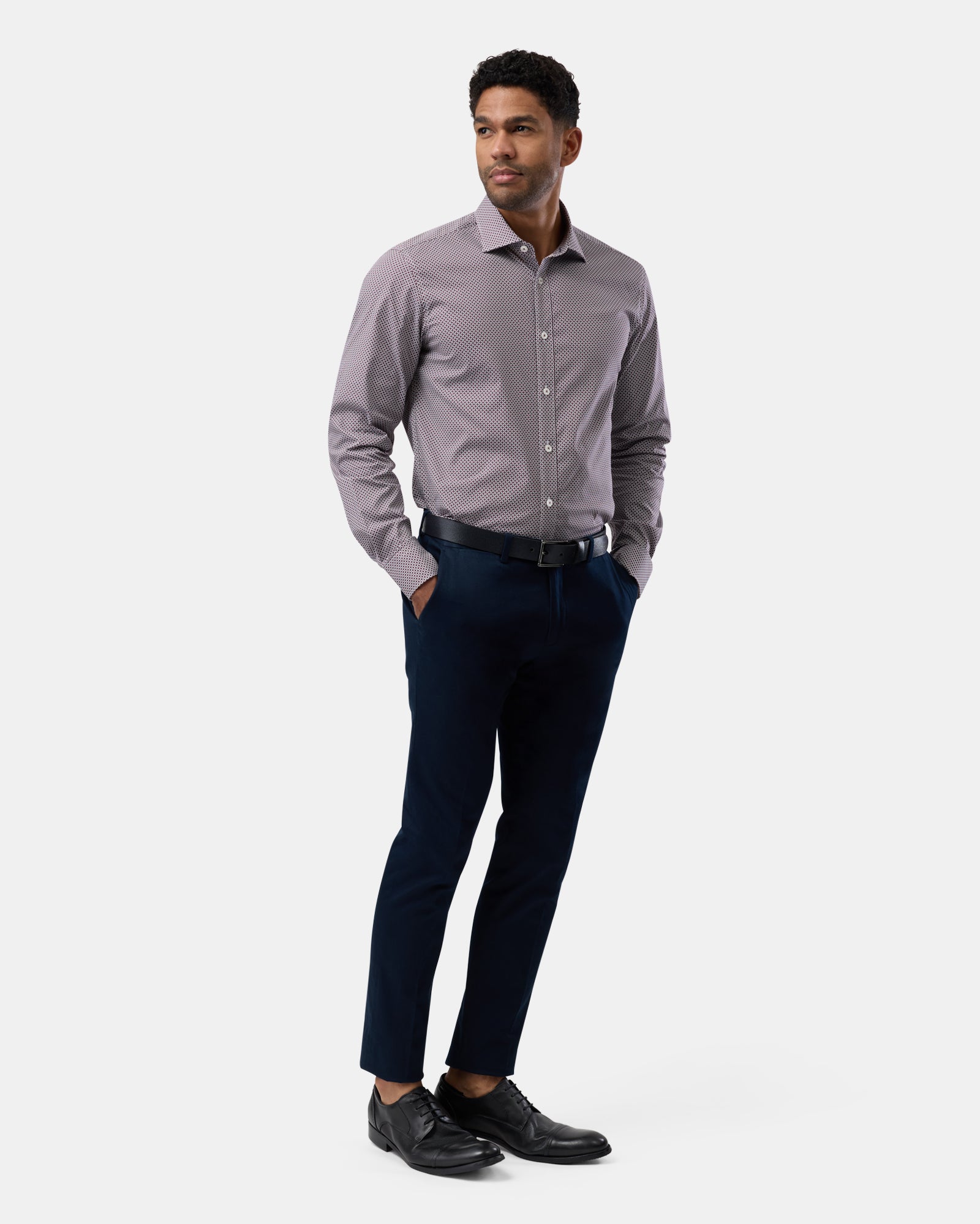 Man wearing a burgundy geometric patterned shirt in a full-body view