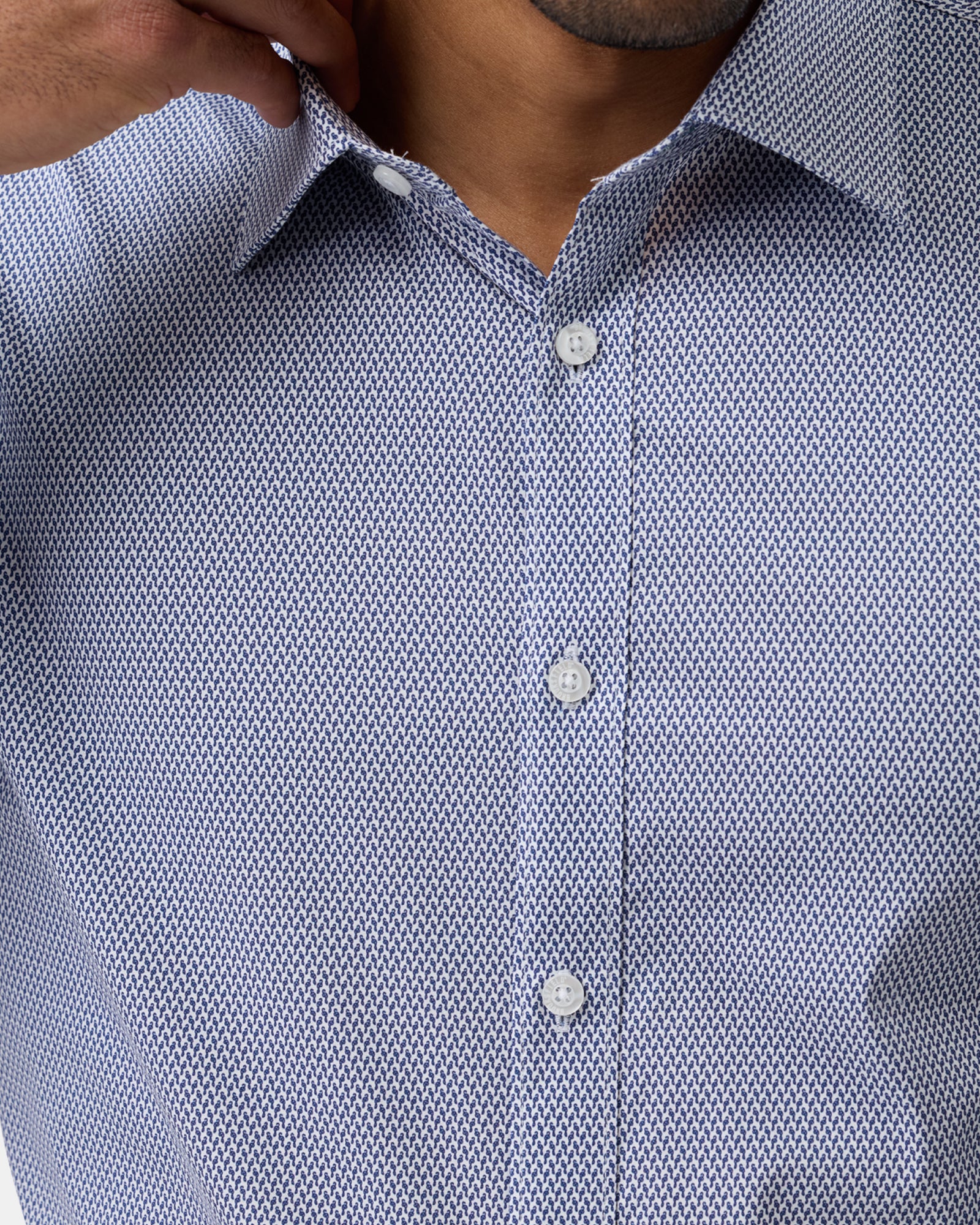 Close-up of blue geometric stretch performance shirt, detailing fabric texture, pattern, and buttons