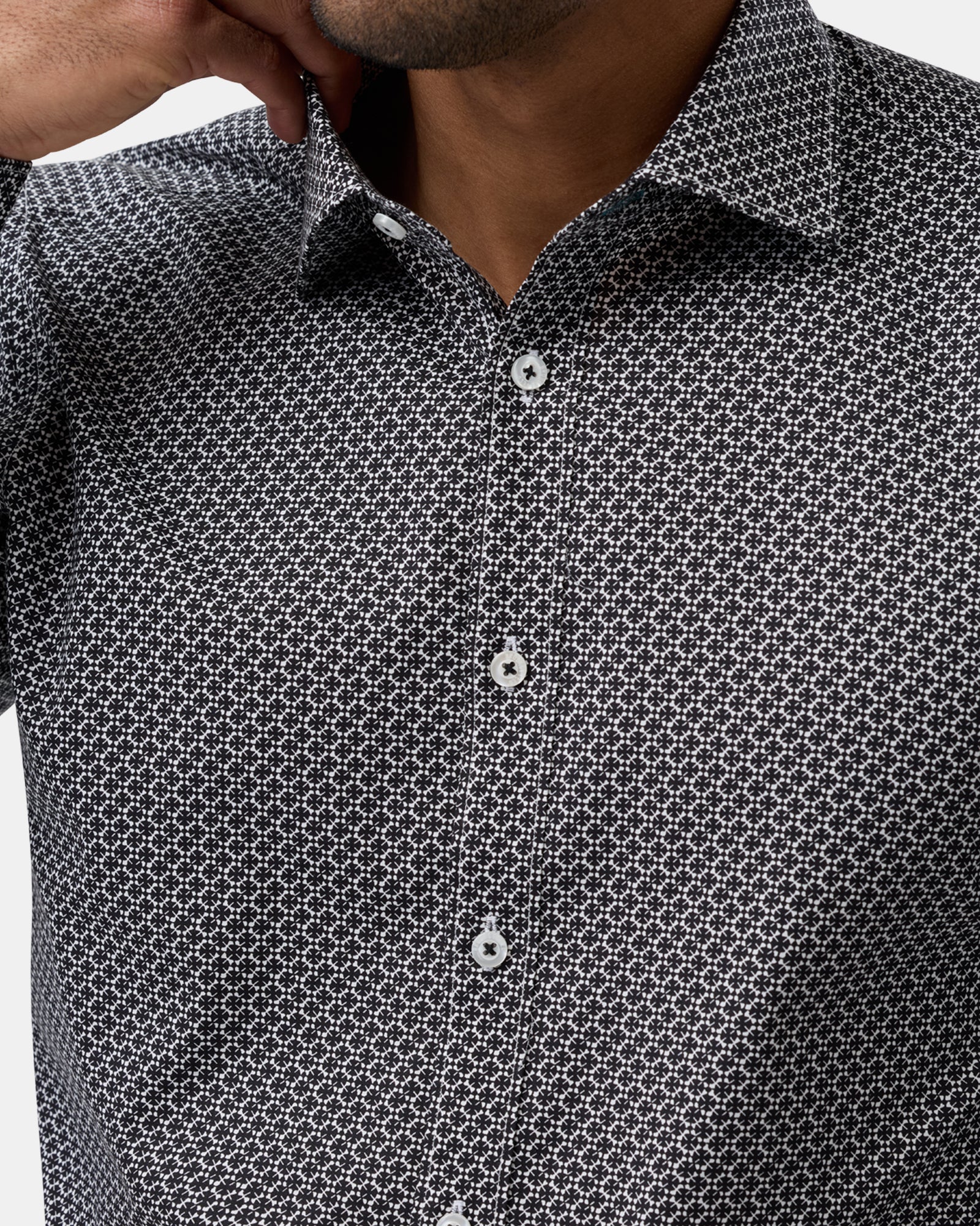 Close-up of black patterned shirt, detailing fabric texture, buttons, and stitching