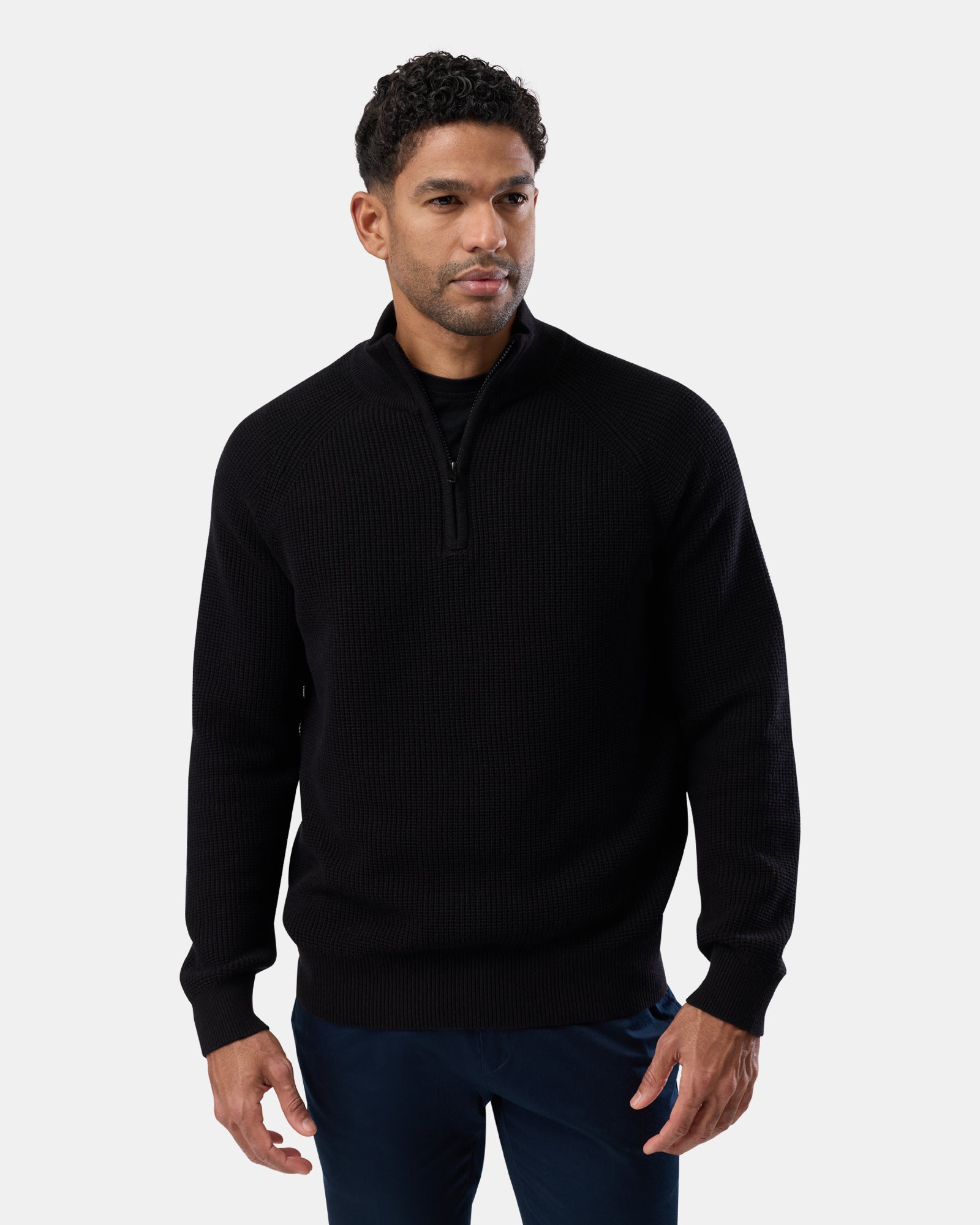 Man wearing a sleek black cotton half zip knit sweater